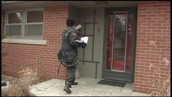A Canada Post letter carrier makes a delivery; December 11, 2013
