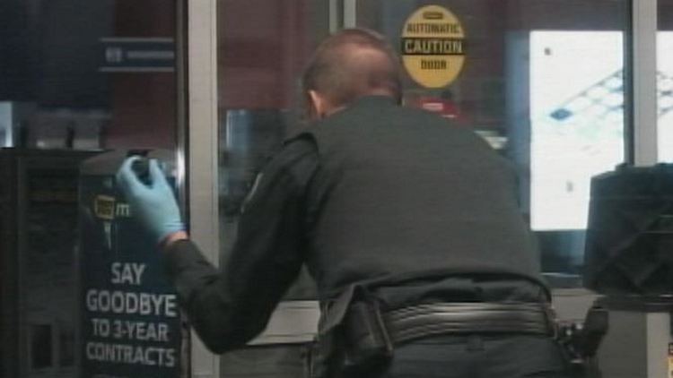 A police officer looks for evidence at a burgled Best Buy in Etobicoke; September 14, 2014