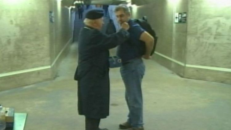 Singing vet Bill Reid pins a poppy on a commuter