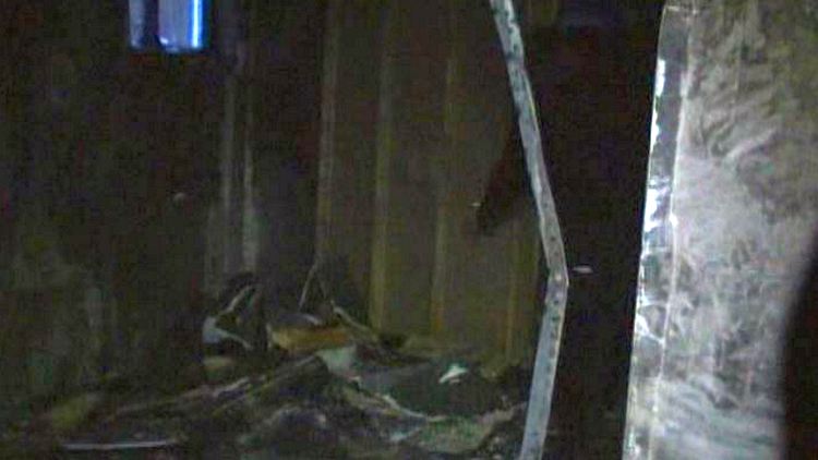 A firefighter inspects a basement gutted by fire; Hamilton, March 5, 2015