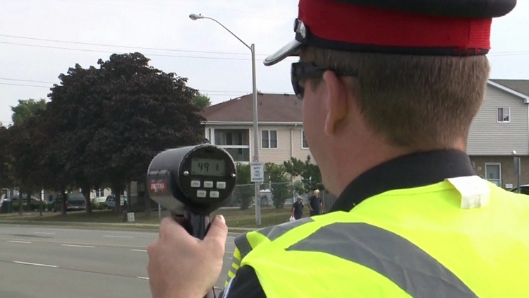 A Niagara Police officer holds up a radar gun to monitor back-to-school traffic; September 8, 2015