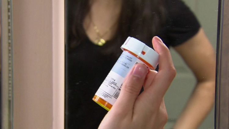 Archive image of a woman holding a bottle of prescription pills