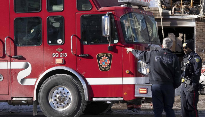 A fire official and police officer talk at the scene of a fatal house fire in Brampton, Ont., Thursday, Jan. 20, 2022.